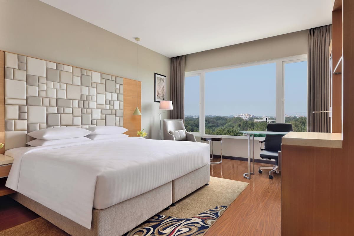 Ein modernes Hotelzimmer mit einem großen Bett, einem Schreibtisch und Blick auf die Stadt.