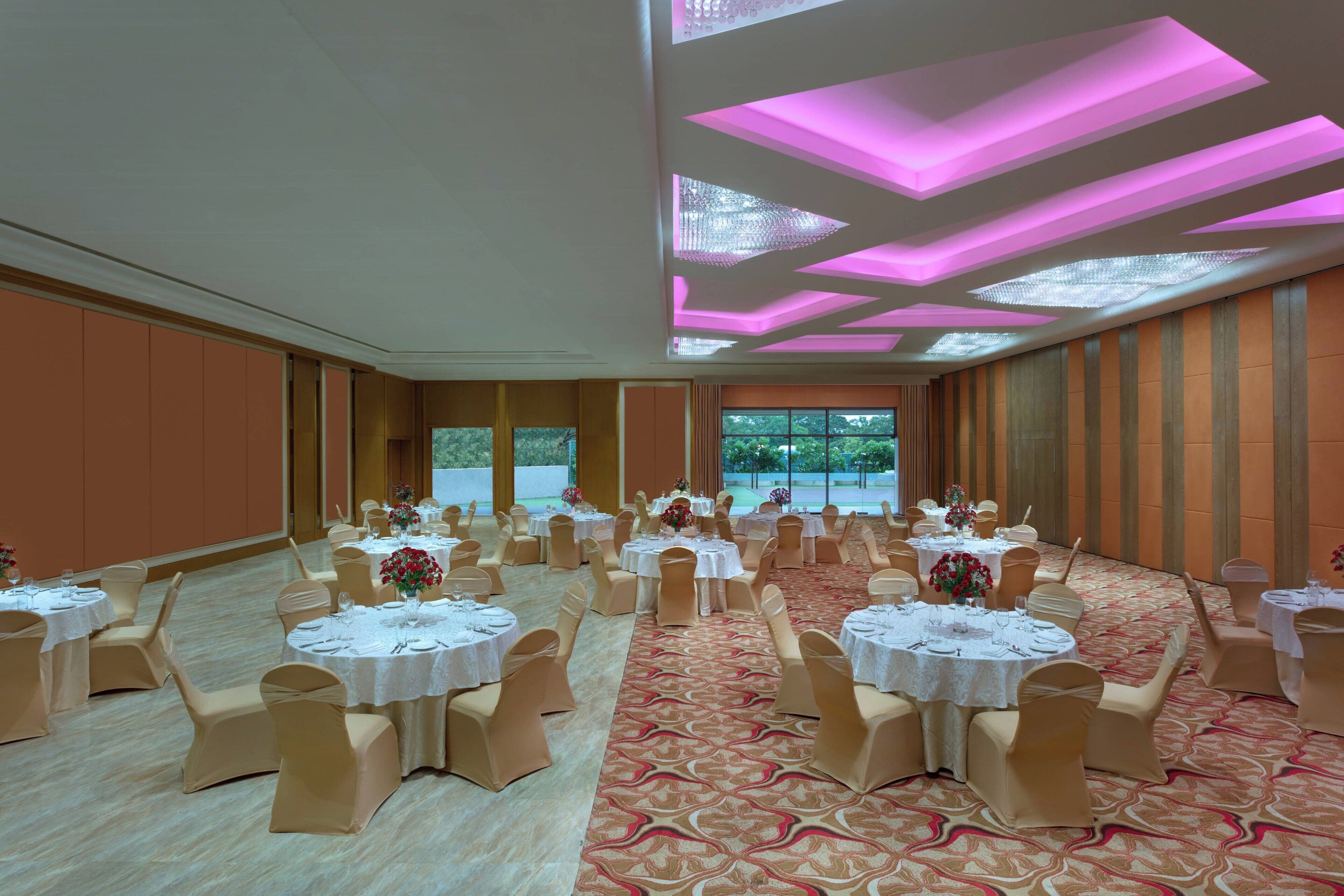 A banquet hall with round tables, beige chairs, and a patterned carpet.