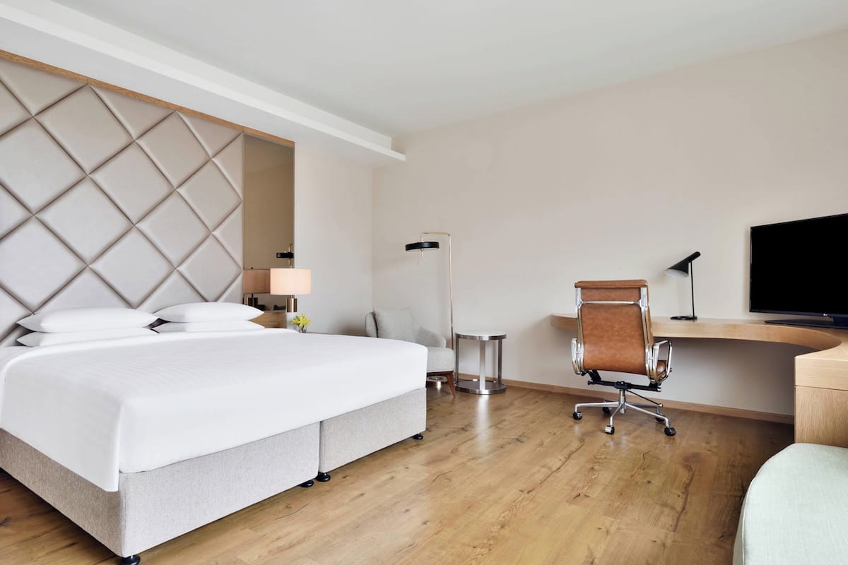 Ein Hotelzimmer mit einem großen Bett, einem Schreibtisch, einem Stuhl, einem Fernseher und einer Lampe.