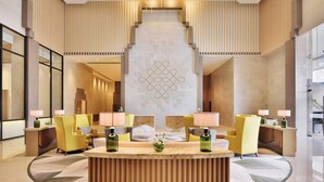 A modern hotel lobby with a central reception desk, seating area, and a staircase leading to upper floors. - Courtyard by Marriott Madurai (Madurai)