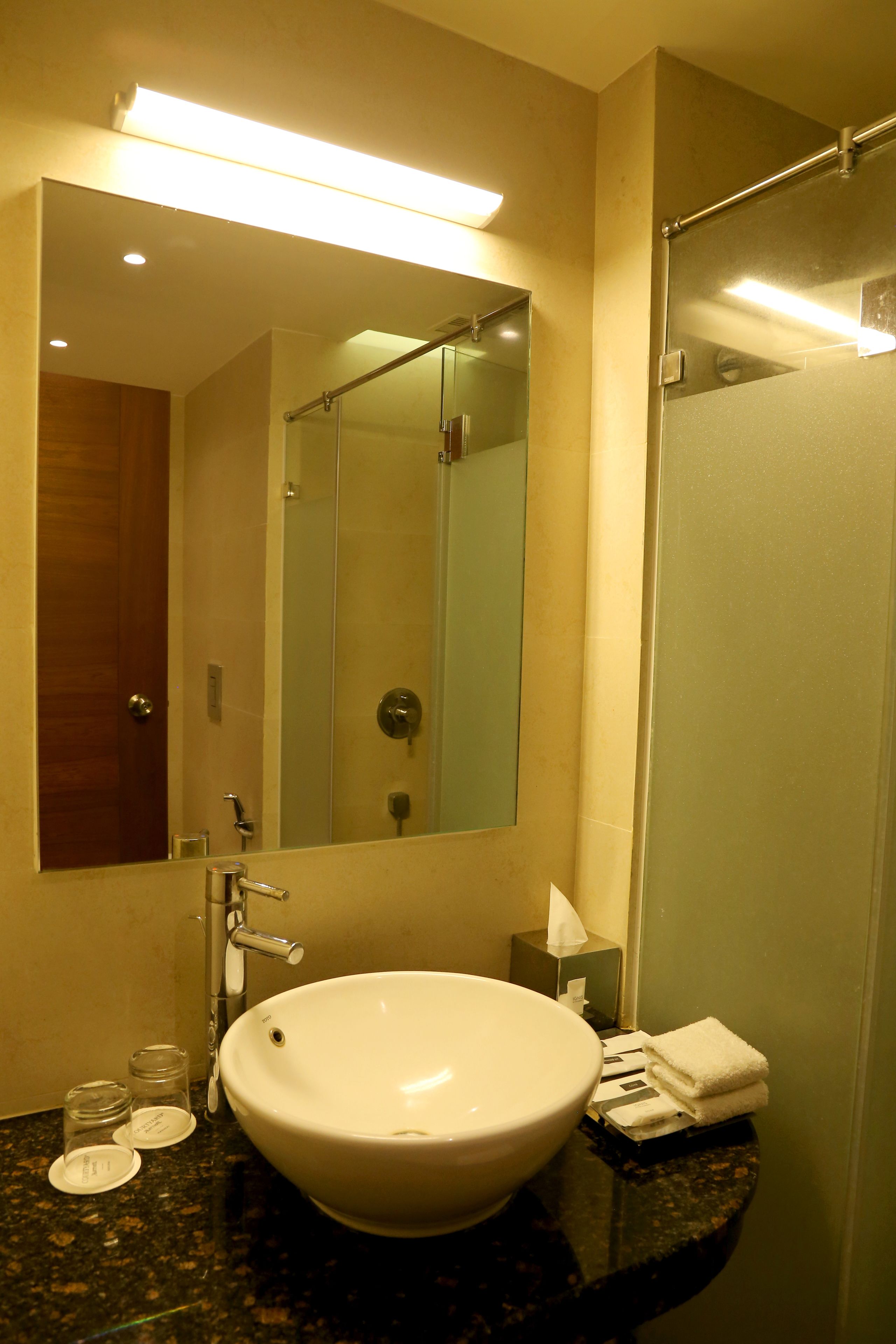A bathroom with a large sink, mirror, and glass shower enclosure.