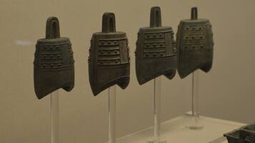 Four metal objects on display, each mounted on a clear stand.