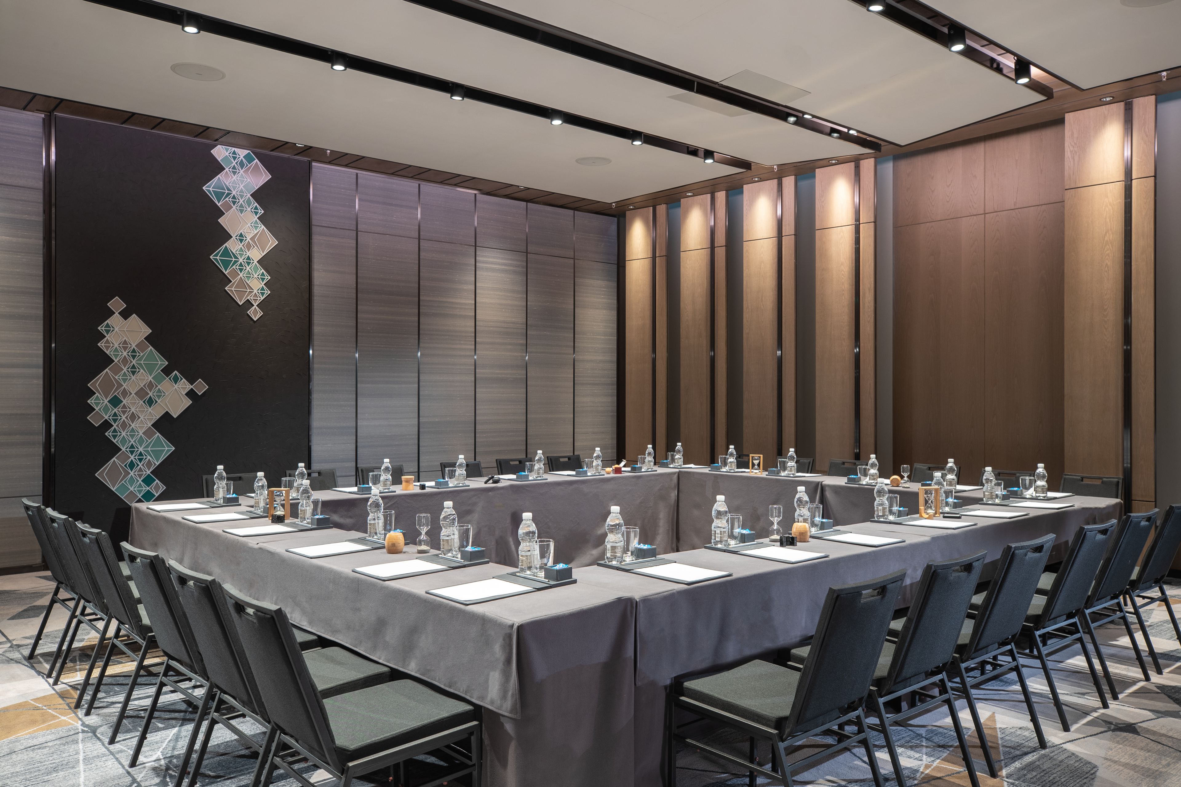 Une salle de conférence avec une longue table, des chaises et des bouteilles d’eau.