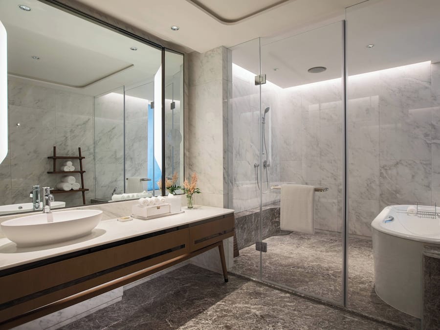 A modern bathroom with a large mirror, a vessel sink, a separate bathtub, and a glass-enclosed shower area.