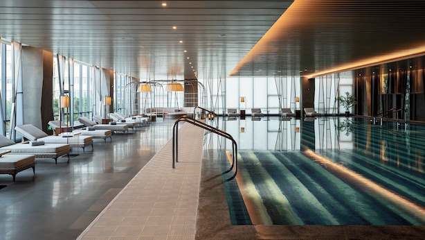 A modern indoor swimming pool area with lounge chairs and a glass barrier. - Renaissance Xi'an Hotel (Xi'an)