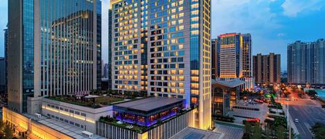 A high-rise hotel with multiple floors, a rooftop terrace, and a well-lit entrance.