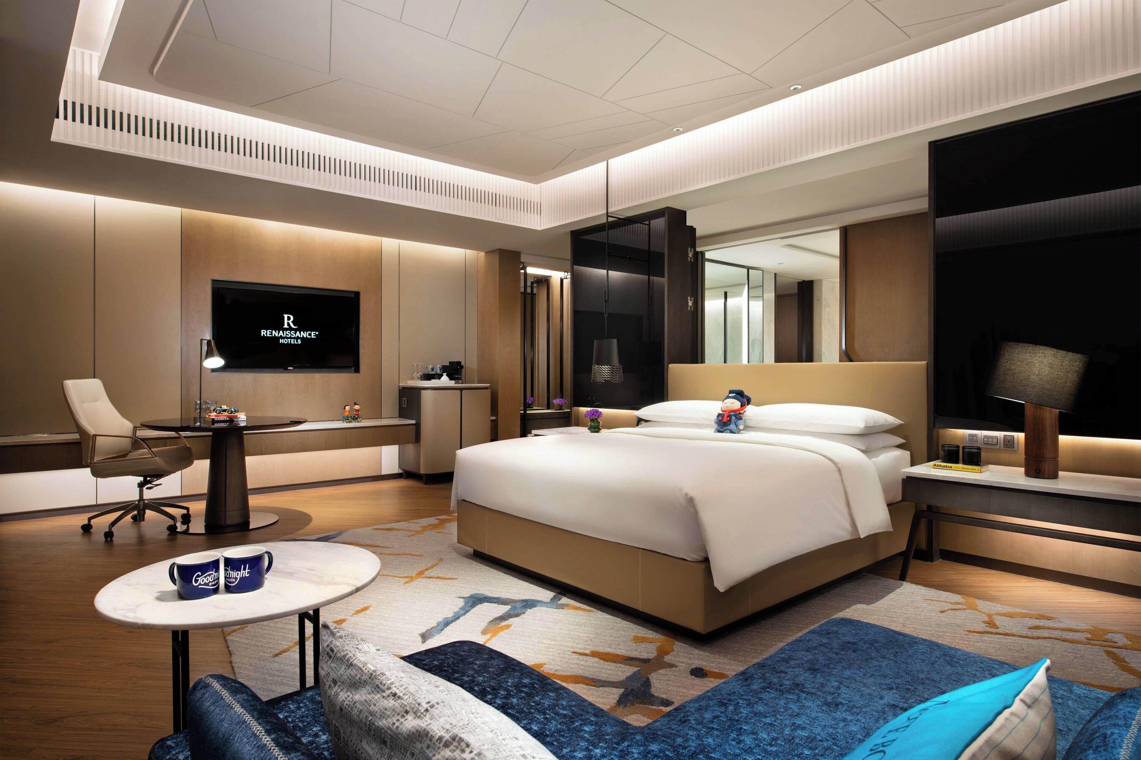 Une chambre d’hôtel moderne dotée d’un grand lit, d’une télévision, d’un bureau et d’un coin salon confortable.