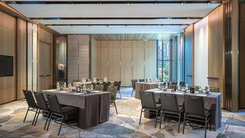 Un salón de conferencias con varias mesas y sillas, ventanas amplias y un diseño moderno.