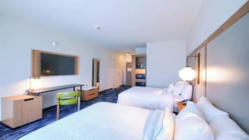 Habitación de hotel con dos camas, un escritorio, una silla, un televisor y un espejo.