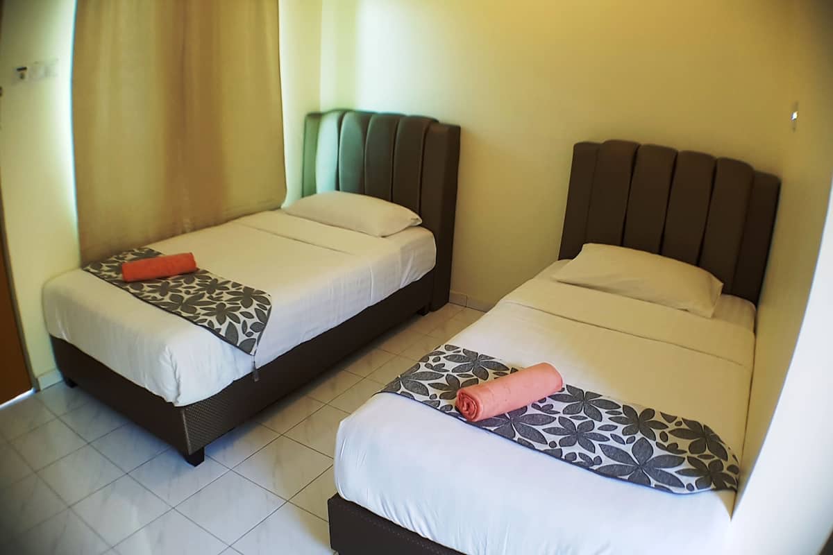 Two single beds with headboards, a patterned bedspread, and a rolled towel on each bed.