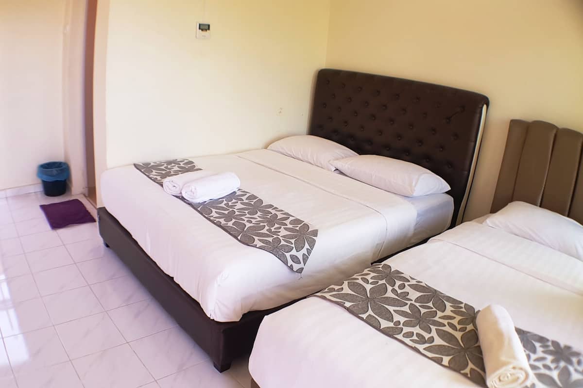 A hotel room with two beds, each with white linens and patterned bedspreads.