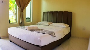 A neatly made bed with white linens and a patterned throw, a window with a view of greenery, and a brown headboard.