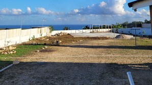 An outdoor area with a concrete floor, a white wall, and a view of the ocean.