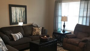 A living room with a sectional sofa, a coffee table, and a floor lamp. - Lyndale House: Full house with 3 br (Corning)