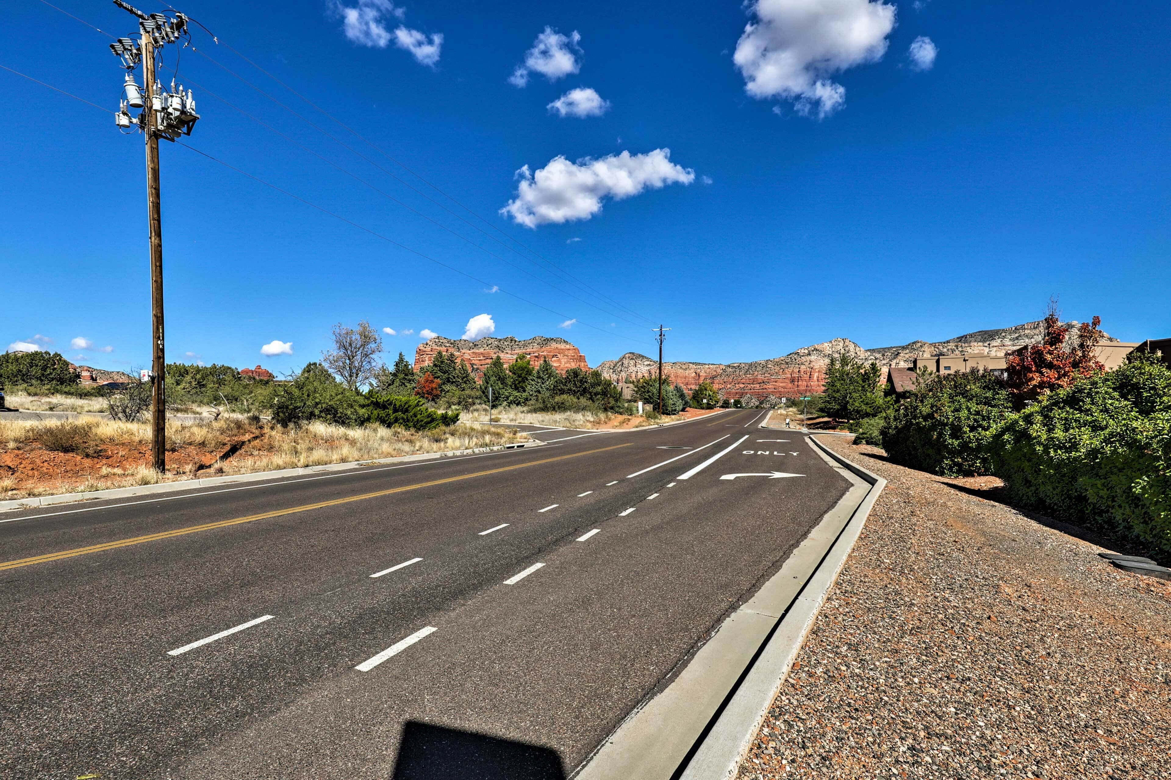 Una carretera bajo un cielo despejado, con una montaña al fondo y un poste de servicios a la izquierda.