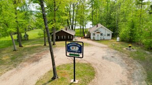 Opastekyltti, jossa lukee ”Paradise Lake Cottages”, ja sen jälkeen sorapäällysteinen ajotie, joka johtaa puiseen mökkiin ja valkoiseen rakennukseen.