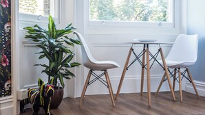 Eine Sitzecke mit zwei weißen Stühlen, einem kleinen Tisch und einem Blumentopf.