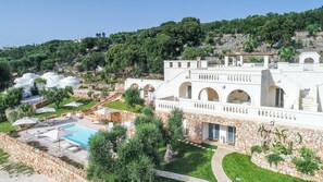 A white building with arched windows and a pool area.