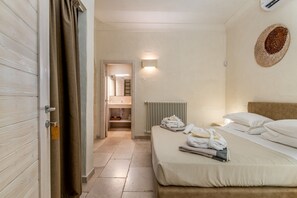 A hotel room with a bed, a bathroom, and a hallway.