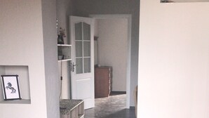A hallway with dark wooden flooring, white walls, and a door leading to another room. - Villa Keshle Baku (Baku)