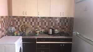 A compact kitchen with a dishwasher, a stove, and a refrigerator. - Villa Keshle Baku (Baku)