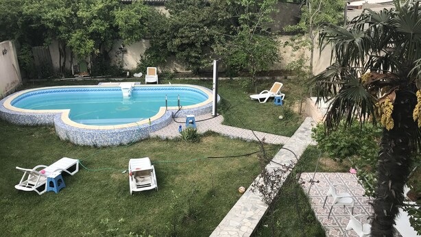 A backyard with a swimming pool, a grassy area, and a stone pathway. - Villa Keshle Baku (Baku)