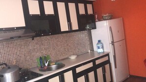 A kitchen with black and white cabinets, a white refrigerator, and a tiled backsplash. - Villa Keshle Baku (Baku)