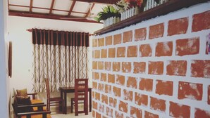 A room with a brick wall, a wooden bench, a chair, and a table. - Villa Hilltop (Hikkaduwa)