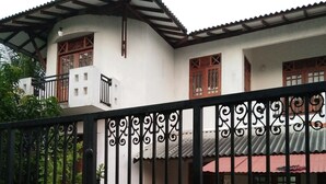 A gated residential area with a white building featuring a tiled roof and wooden window frames. - Villa Hilltop (Hikkaduwa)