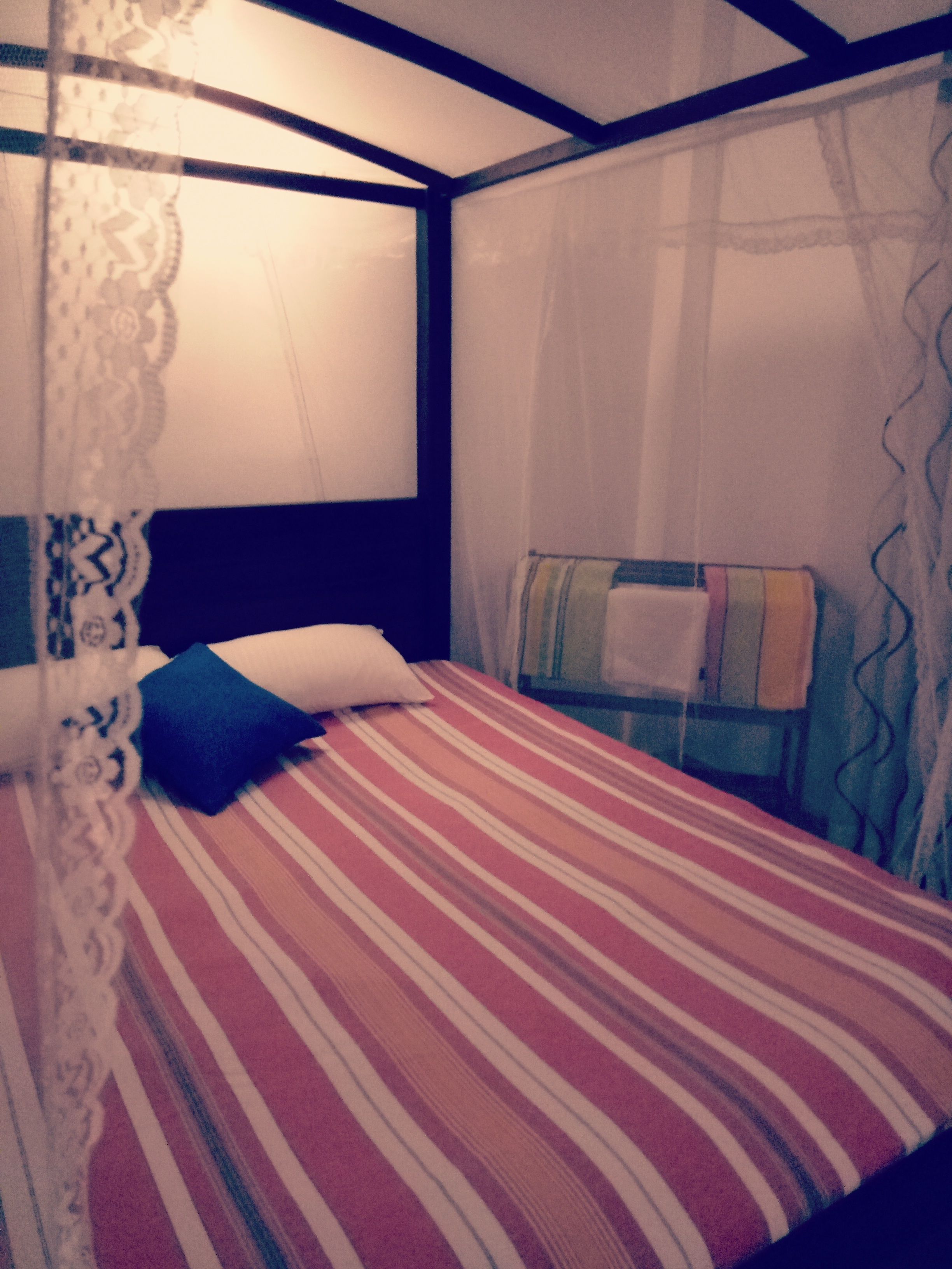 A bed with a striped bedspread, a white pillow, and a blue pillow.