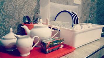 A kitchen counter with a tea set, a box of tea, and a dish rack.