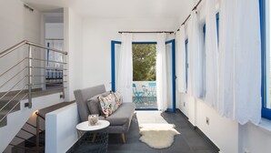 A modern interior with a grey sofa, a small round table, and a staircase with metal railings. - Seaside Luxury Villa with Terrace in Aegina Island | Aneli Villa Aegina (Aegina)