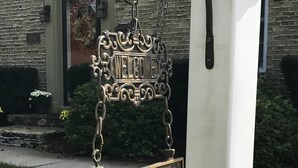 A house sign with the number 1810 and the text "Emerson House" hanging on a white post.