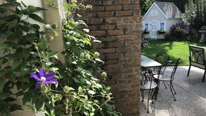 A brick wall with climbing plants and a patio area with a table and chairs.