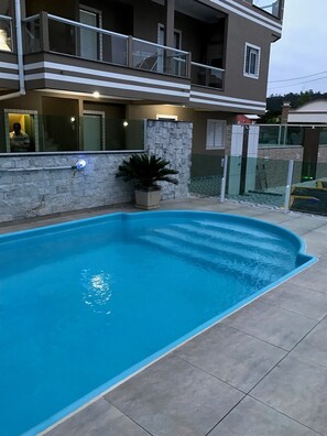 Piscina com parede de pedra e planta em vaso.