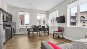A modern apartment with a kitchen, dining area, and living room. It features a flat-screen TV mounted on the wall, a dining table with chairs, and a sofa with red cushions. - Lake Placid Inn Main Street (Lake Placid)