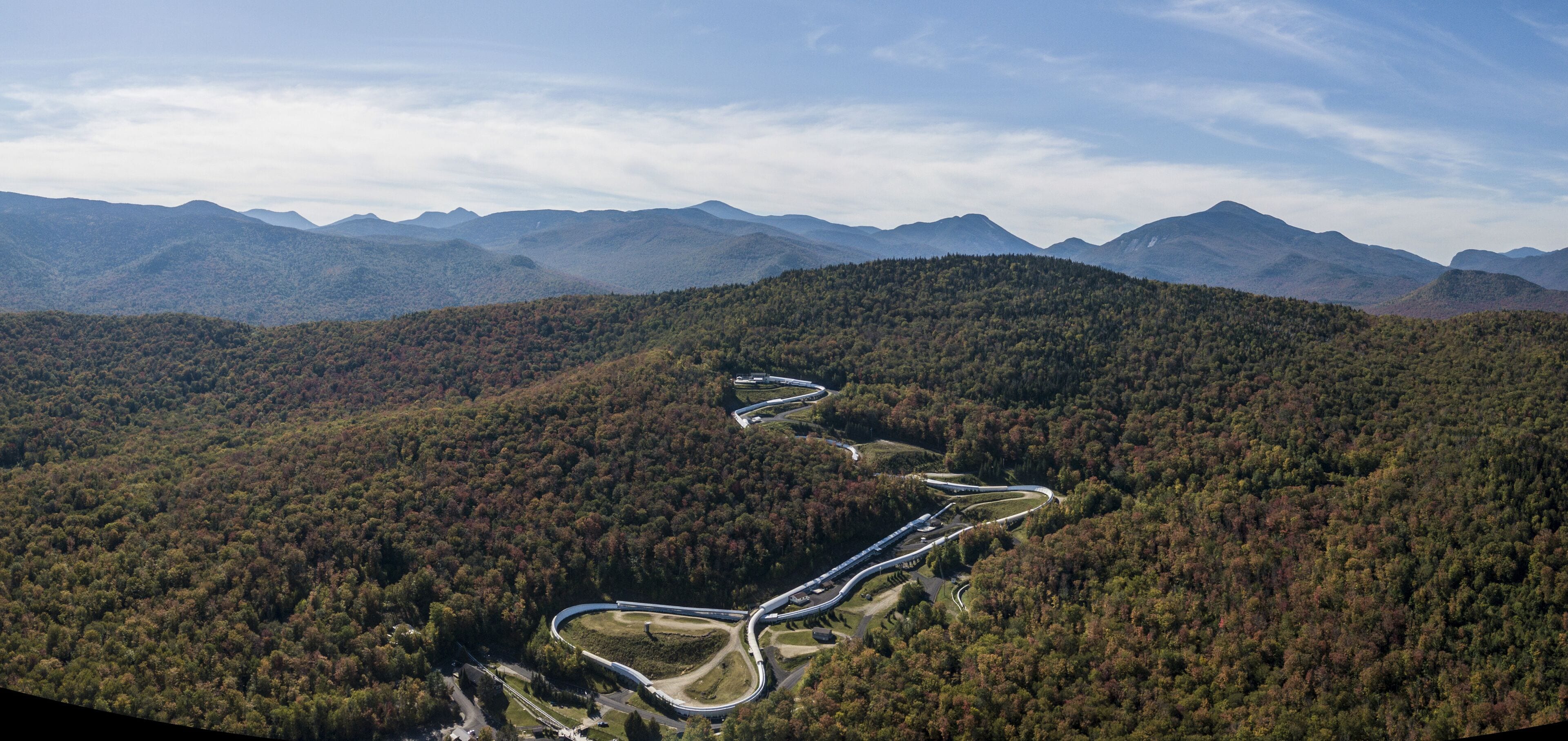 An aerial view of a winding road through a forested mountain area.