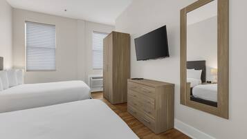 Ein Hotelzimmer mit zwei Betten, einem Fernseher, einem Schminktisch und einem großen Spiegel.