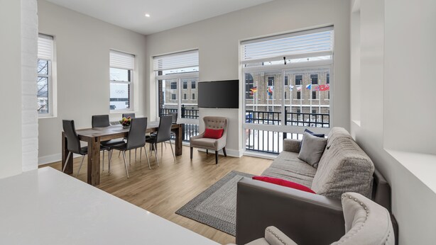 A modern living room with a dining area, large windows, and a balcony with a view. - Lake Placid Inn Main Street (Lake Placid)