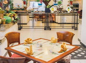 A restaurant with a central bar, wooden chairs, and a table set with a floral tablecloth.