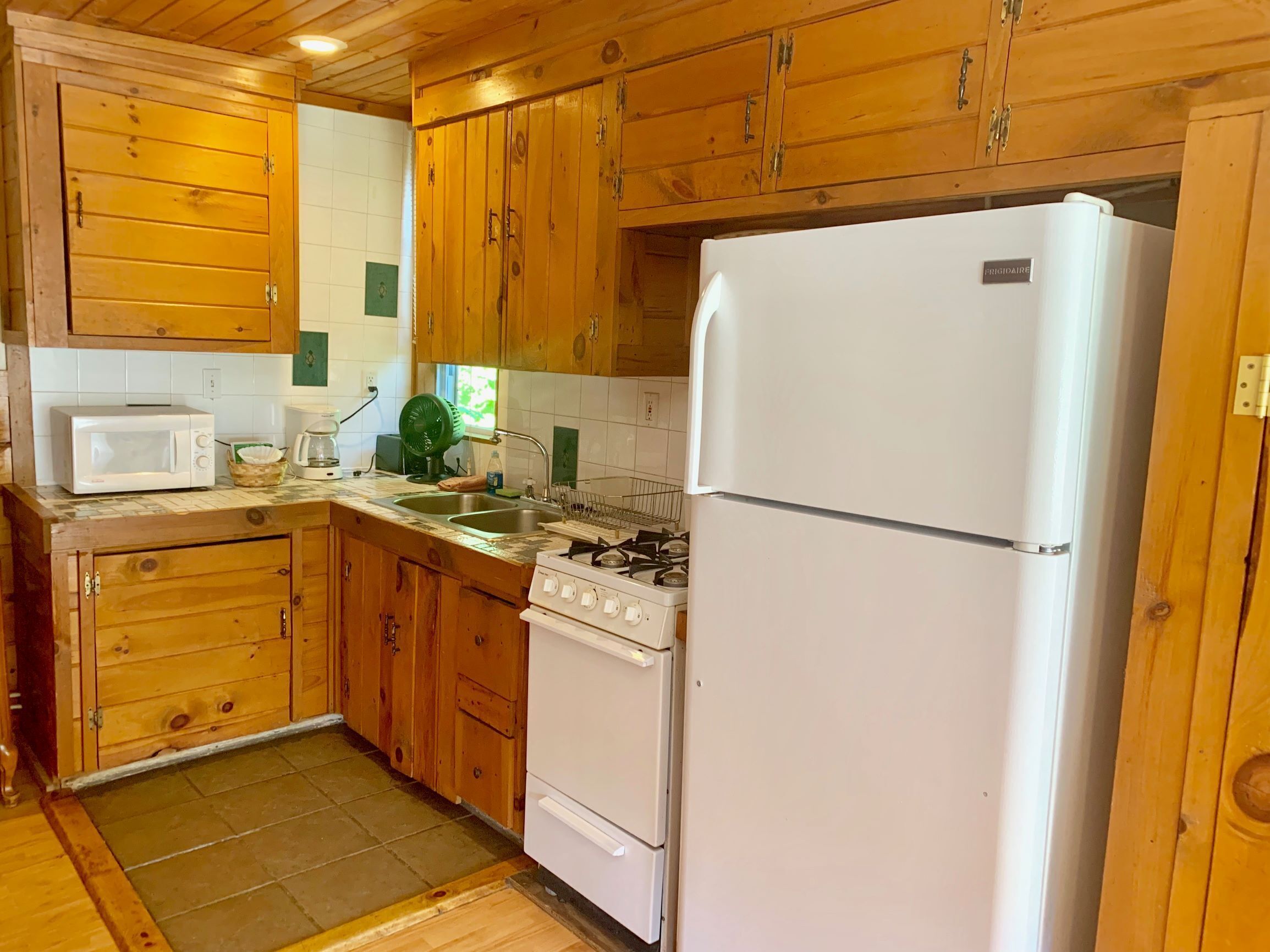 A kitchen with wooden cabinets, a white refrigerator, a stove, and a microwave.