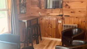 A wooden interior with a bar area, a television mounted on the wall, and black leather seating. - Pine Crest Motel And Cabins (Barton)