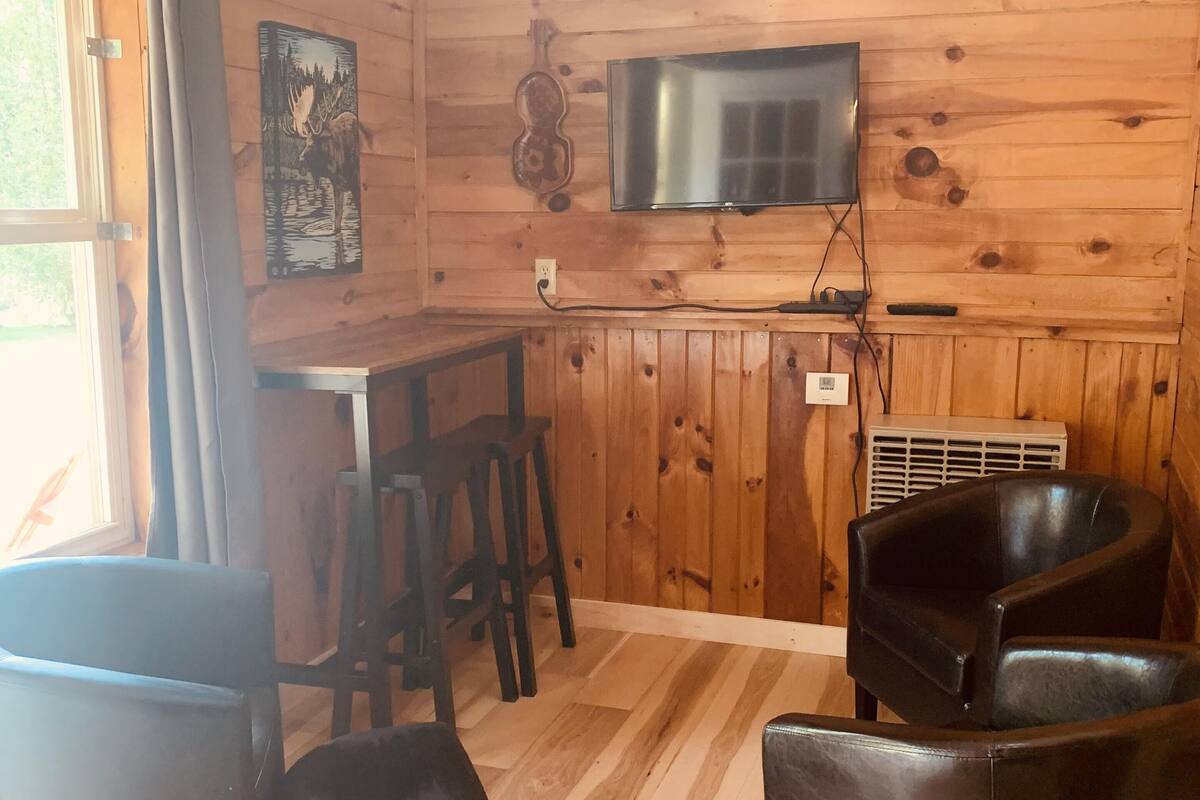 A wooden interior with a bar area, a television mounted on the wall, and black leather seating.