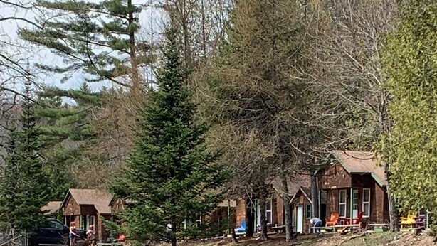 A riverside cabin with outdoor seating and a dock. - Pine Crest Motel And Cabins (Barton)