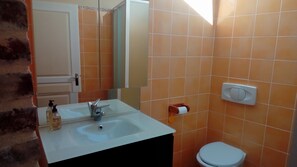 Een badkamer met een wit wastafelmeubel, een spiegel en een toilet.