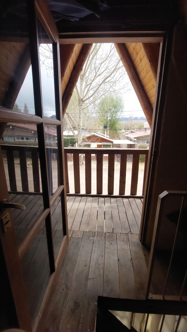 Una terraza de madera con barandilla que da a un balcón con vistas a una zona residencial.