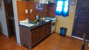 Una cocina compacta con lavamanos, estufa y armarios.