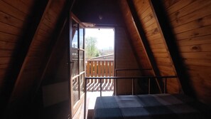 Un interior de madera con un balcón, una ventana y una escalera.