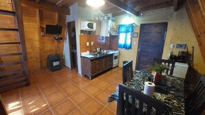 Una cocina con microondas, estufa y lavabo. Hay una mesa de comedor con sillas y una planta.