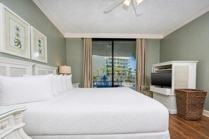 Une chambre d’hôtel avec un grand lit, une télévision, un panier en osier et une vue sur un immeuble et une piscine.